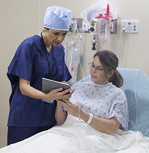 Healthcare provider talking to woman in pre-op hospital room.