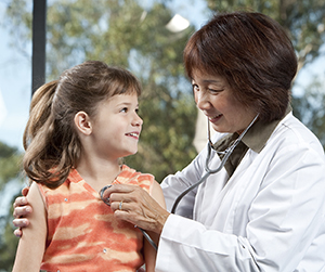 Médico escuchando los sonidos del pecho de una niña con un estetoscopio.